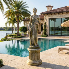 Statue by a pool with a house and palm trees in the background