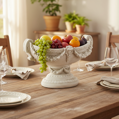 Decorative fruit bowl on a wooden table with glasses and plates in a home setting