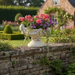 Decorative urn with flowers on a stone wall in a garden setting