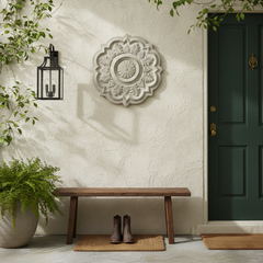 Decorative wall piece above a wooden bench on a porch with a door and plants.