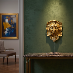 Decorative gold lion head wall piece on a green wall with a marble table below.