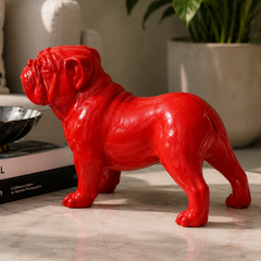 Red bulldog figurine on a marble surface with books and a plant in the background