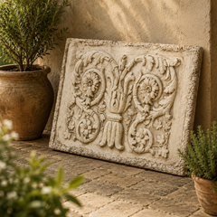 Decorative stone wall art with intricate designs on a patio with potted plants.