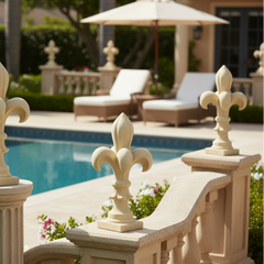 Decorative stone columns with fleur-de-lis designs by a poolside.