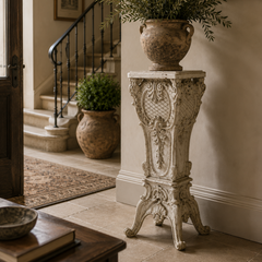 Decorative planters on ornate stands in a home interior.