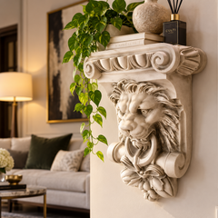 A decorative lion-head wall corbello shelf mounted on a cream wall in a styled living room. The shelf is carved in a light stone-like finish and holds a potted green trailing plant, a textured vase, and a black reed diffuser.