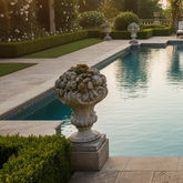 Decorative stone urn by a pool with manicured garden