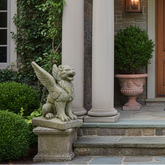 Decorative entrance with wooden door, columns, and gargoyle statues.