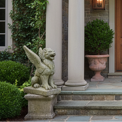 Decorative entrance with wooden door, columns, and gargoyle statues.