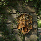 Decorative lion head sculpture on a stone wall with ivy