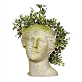 Decorative head sculpture with greenery on a white background