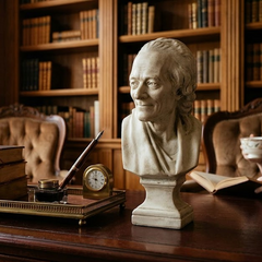 Bust of a person on a desk with books and a clock in a library setting