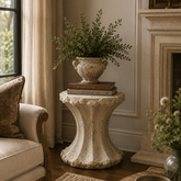 Living room with beige sofa, decorative table, and potted plant.