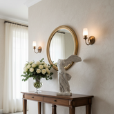 Decorative interior with a wooden console table, statue, and mirror.