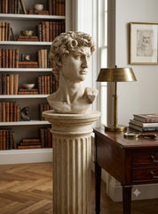 Bust on a pedestal in a room with books and a lamp