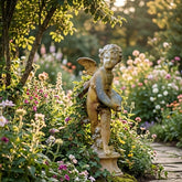 Statue of a angel in a garden with flowers and a stone path