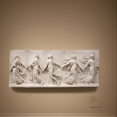 White marble relief sculpture in a museum setting with people observing.