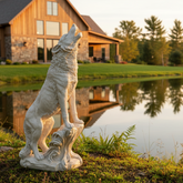 Statue of a howling wolf by a pond with a house in the background
