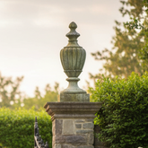 Decorative garden gate with stone pillars and white flowers on a sunny day.