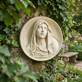 Circular cast stone roundel with the veiled Virgin Mary in relief, mounted on an ivy-covered garden wall