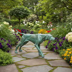 Statue of a dog in a garden with flowers and a stone path