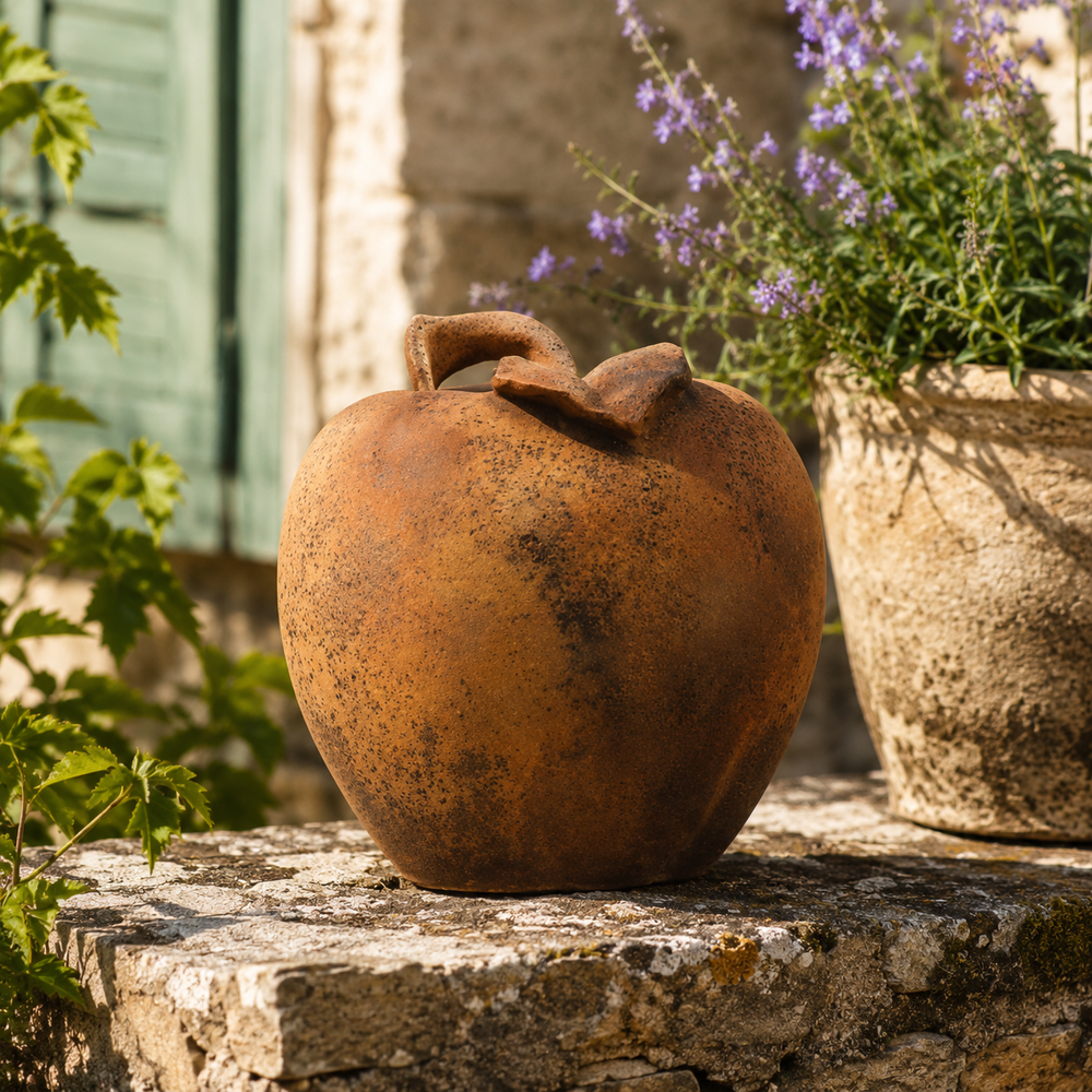 Rust-colored decorative pot on a stone ledge with a blurred background of plants and a building.