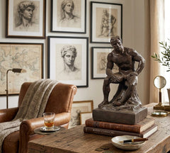 Statue on books on a wooden table with classical art and decor in the background