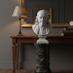 Benjamin Franklin Bust on a pedestal in a room with a lamp and framed pictures on the wall.