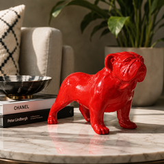 Red bulldog figurine on a marble surface with books and a plant in the background