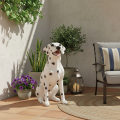 Dalmatian dog sitting on a patio with plants and outdoor furniture.
