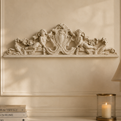 Decorative wall piece above a shelf with books, a candle, and a lamp.