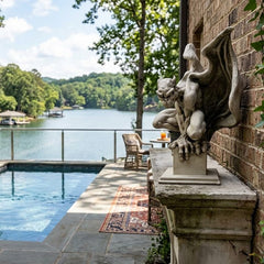 Gargoyle statue by a pool with a scenic lake view