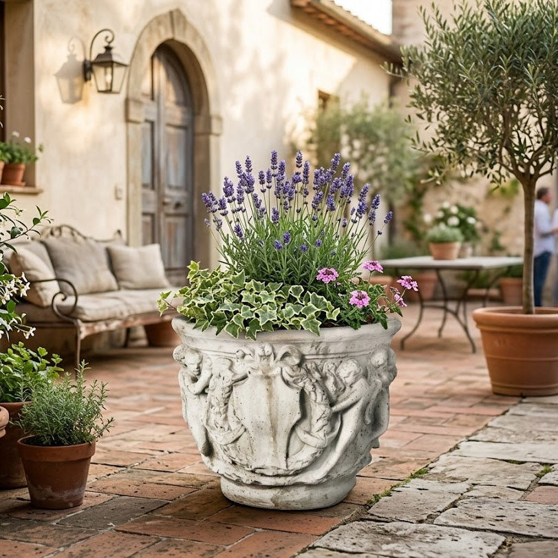 Decorative stone planter with flowers on a patio with people in the Elegant Cherub Bell Pot — Planter background
