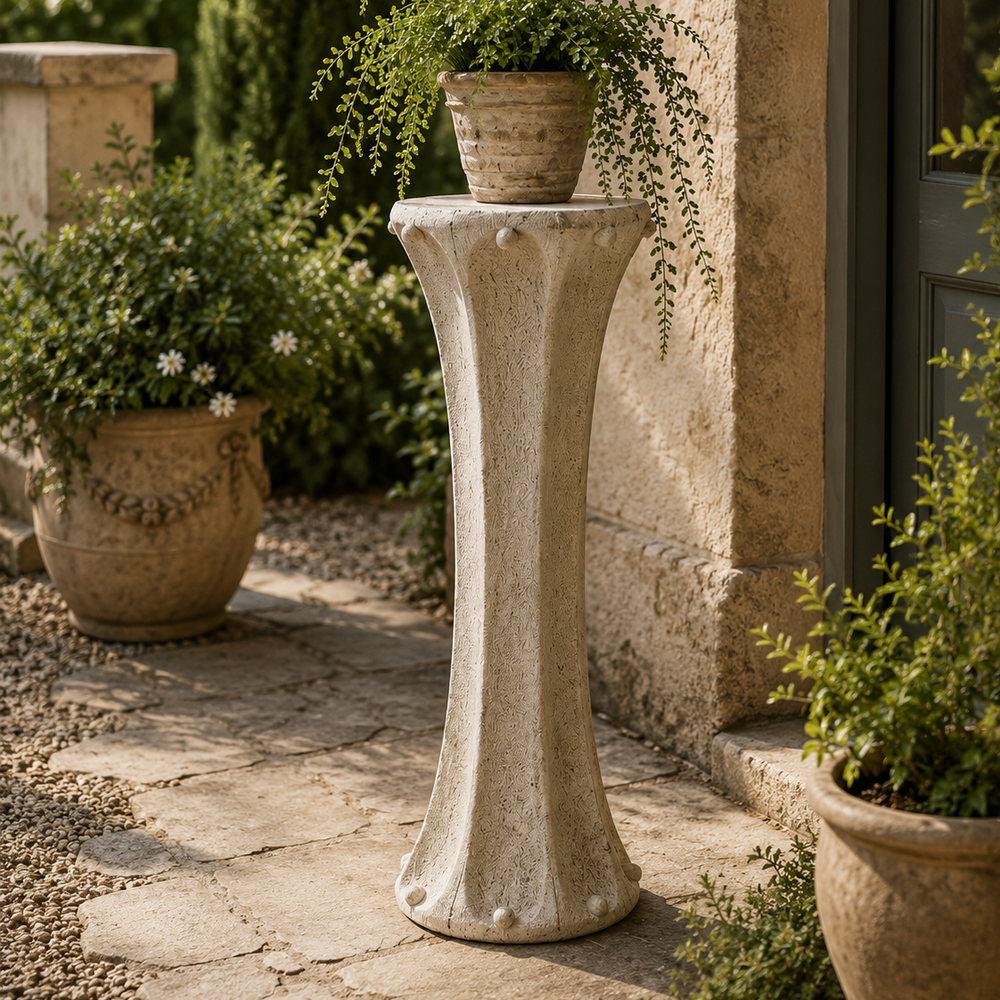 Decorative stone pedestal with a potted plant in an outdoor setting.