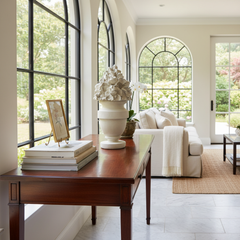 Living room with a wooden coffee table, white sofa, and large windows.