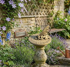 Decorative sundial in a garden with flowers and a bench in the background
