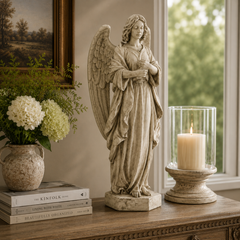 Statue of an angel on a wooden surface with books and a candle