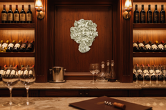 Wine bar with wine bottles, glasses, and a decorative wall piece.