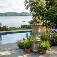 Outdoor setting with a pool, garden, and scenic view of water and mountains.