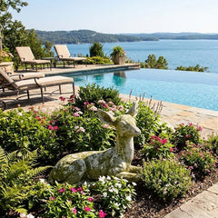 Pool area with lounge chairs, decorative deer statue, and scenic lake view.