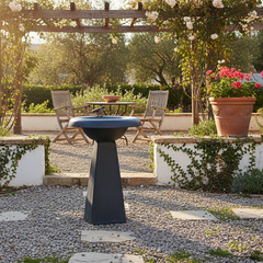 Outdoor garden setting with a birdbath, chairs, and potted plants.