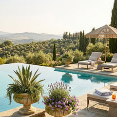 Outdoor pool area with lounge chairs, umbrellas, and decorative plants in Tuscany.