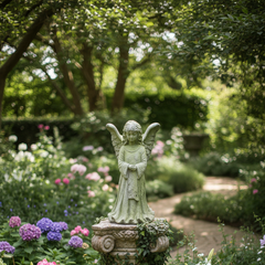 Statue of an angel in a garden with flowers and trees