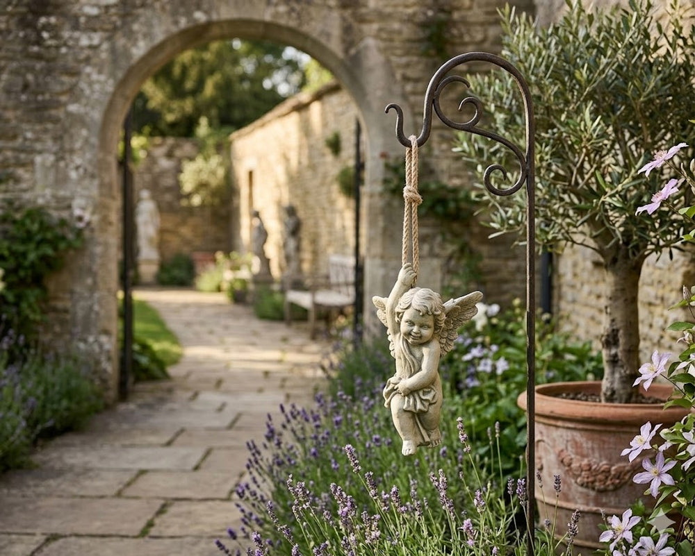 Garden scene with a stone archway, potted plants, and a decorative angel figure on a swing.